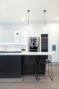 a kitchen with two black chairs and an island in front of the stove top oven