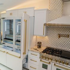 a kitchen with white cabinets and gold trimmings on the backsplashes