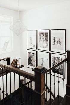 black and white photos hang on the wall next to a stair case in a home