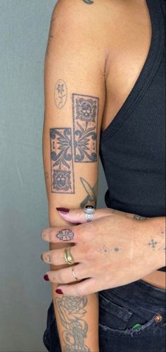 a woman's arm with tattoos on it and a cross tattooed on the wrist