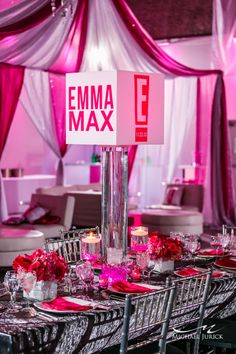 the table is set for an event with pink flowers and candles on it, as well as a sign that says emma max