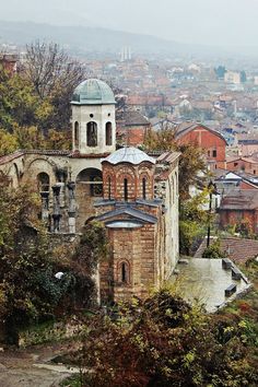 an old building in the middle of a city with lots of trees and buildings around it