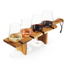 three glasses of wine sit on a wooden bench