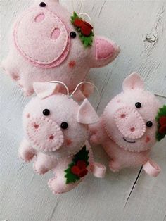 three pink stuffed pigs hanging from strings on a white wooden surface with red flowers and leaves