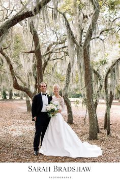 a bride and groom standing in front of trees with spanish moss hanging from the branches