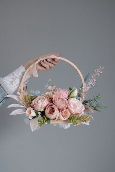 a woman is holding a basket with flowers in it and her hand on the handle