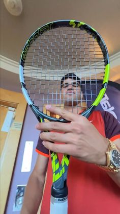 a man holding a tennis racquet in his right hand while wearing a watch