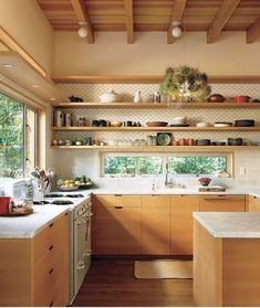 a kitchen with wooden cabinets and white counter tops next to an open window overlooking the woods