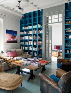 a living room filled with lots of furniture and bookshelves covered in blue bookcases