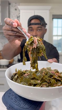 a man is eating greens in a white bowl