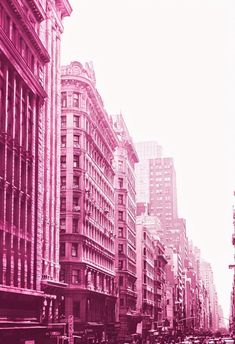 a city street filled with lots of tall buildings and cars driving down one side of the road