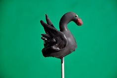 there is a black duck on top of a cake stick with chocolate icing and sprinkles