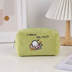 a small green bag with a cartoon character on it sitting on a desk next to a lamp