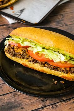 a sandwich with lettuce, tomato and meat on it sitting on a plate