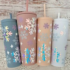 four different colored tumblers with snowflakes on them, one has a straw in it