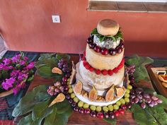 a three tiered cake with fruits and vegetables on the top is surrounded by flowers