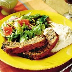 a yellow plate topped with meat, mashed potatoes and salad