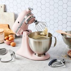 a pink mixer sitting on top of a counter next to other kitchen accessories and utensils