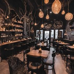 the interior of a restaurant with wooden tables and black walls, hanging lights and chandeliers