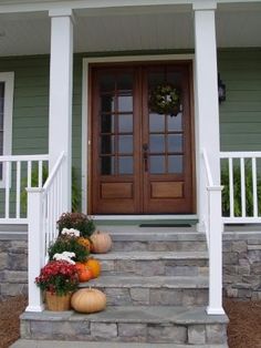 a front porch with pumpkins and gourds on the steps