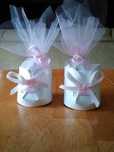 two small white boxes with pink bows on them sitting on top of a wooden table