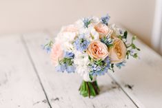 a bouquet of flowers sitting on top of a white wooden table next to a window