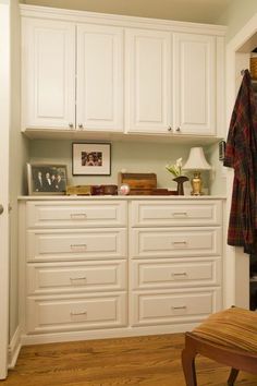 a white closet with many drawers and pictures on the wall