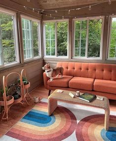 a living room with an orange couch and colorful rugs on the hardwood flooring