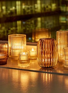 candles are lined up on a window sill in front of a cityscape