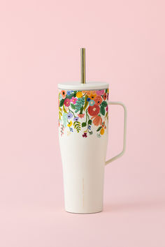 a white coffee cup with flowers painted on the side and a straw sticking out of it