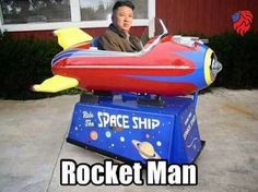 a man sitting on top of a rocket ship ride in front of a house with the caption rocket man