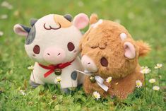 two stuffed animals sitting in the grass next to each other with one cow holding a knife