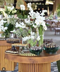 a table topped with lots of vases filled with white flowers and food on top of it