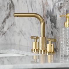 two gold faucets on a marble counter top