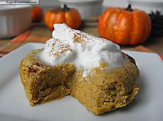 a pumpkin pie with whipped cream on top sits on a white plate next to other pumpkins