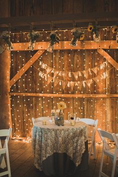 a wooden barn with lights strung from the ceiling and tables set up for an event