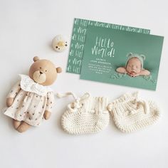 there is a teddy bear and two knitted mittens next to a baby's birth card