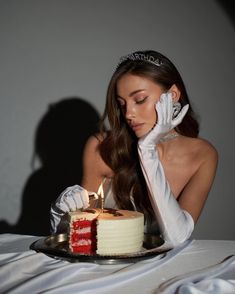 a woman in white gloves is blowing out the candles on a red and white cake