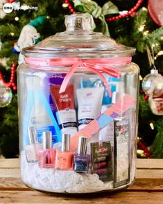 a glass jar filled with lots of beauty products on top of a wooden table next to a christmas tree