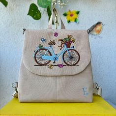 a purse with flowers and a bicycle on it sitting on top of a yellow table