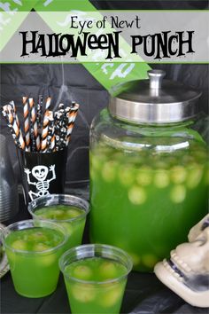 halloween punch with green liquid and candy canes in glasses on the table next to it