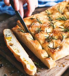 someone cutting bread with a knife on a wooden board