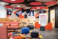 an office with orange and blue chairs, round rugs, and colorful artwork on the walls