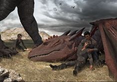 two men are sitting on the ground next to an enormous dragon and another man is standing behind them