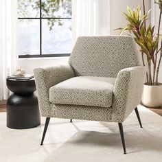 a living room with a chair, potted plant and window in the back ground