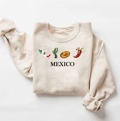 Shop our collection of Mexico flag sweatshirts featuring iconic Mexican symbols like the sombrero mariachi, hot chili pepper, and cactus. Perfect for celebrating Cinco de Mayo, Dia De Los Muertos, or giving as a gift for the holidays. Show off your Mexican pride with this beige crewneck sweatshirt inspired by Anfora Mexico, Sayulita Mexico, and Nayarit Mexico. Get into the holiday spirit with our Feliz Navidad Shirt, Mexican Christmas, Felices Fiestas Gift, and other festive designs like Pan Dul Mexico Cricut, Mexico Jacket, Mexico Tshirts, Mexican Symbols, Mexico Tank Top, Beige Crewneck, Mexican Pride, Mexico Shirts, Gold Shirt