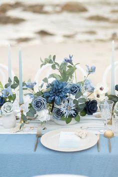 the table is set with blue flowers and candles for an elegant touch to the place setting