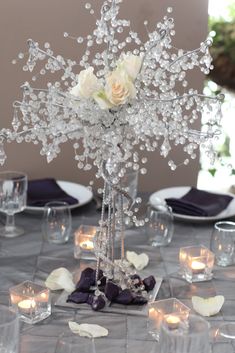 the centerpiece is made out of crystal beads and white roses with candles in them