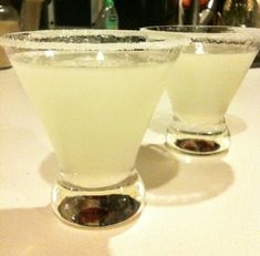 two glasses filled with white liquid sitting on top of a table next to each other