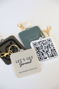 three different key chains with qr code tags attached to them, on a white surface